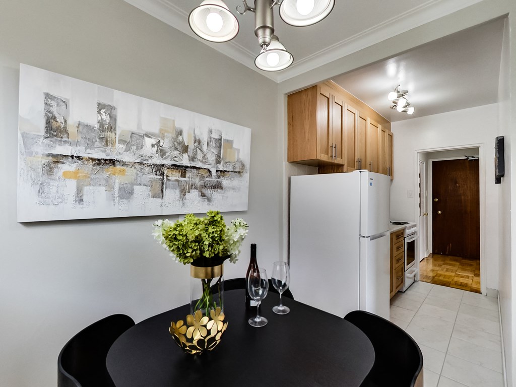 a kitchen and dining room with a black table and chairs and a refrigerator