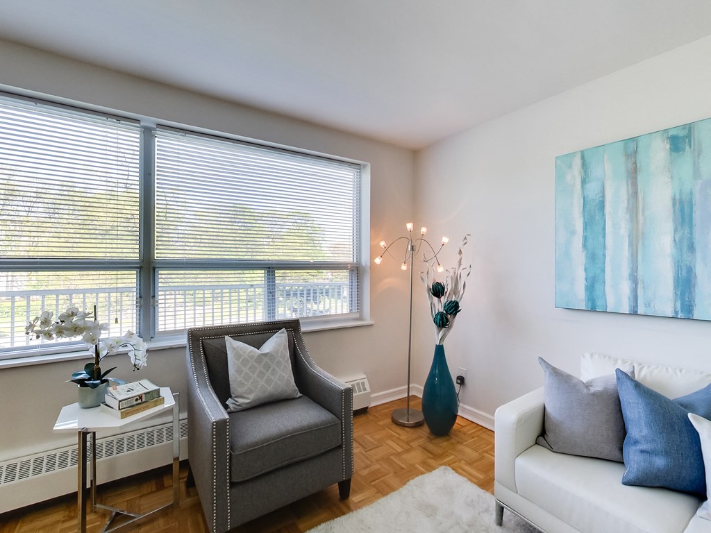 a living room with a couch and a chair and two windows