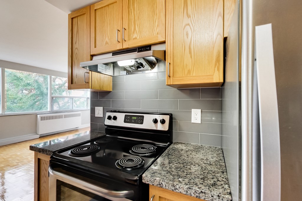 an empty kitchen with granite countertops and a black stove