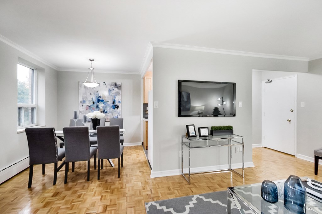 a living room with a dining room table and chairs and a tv on the wall