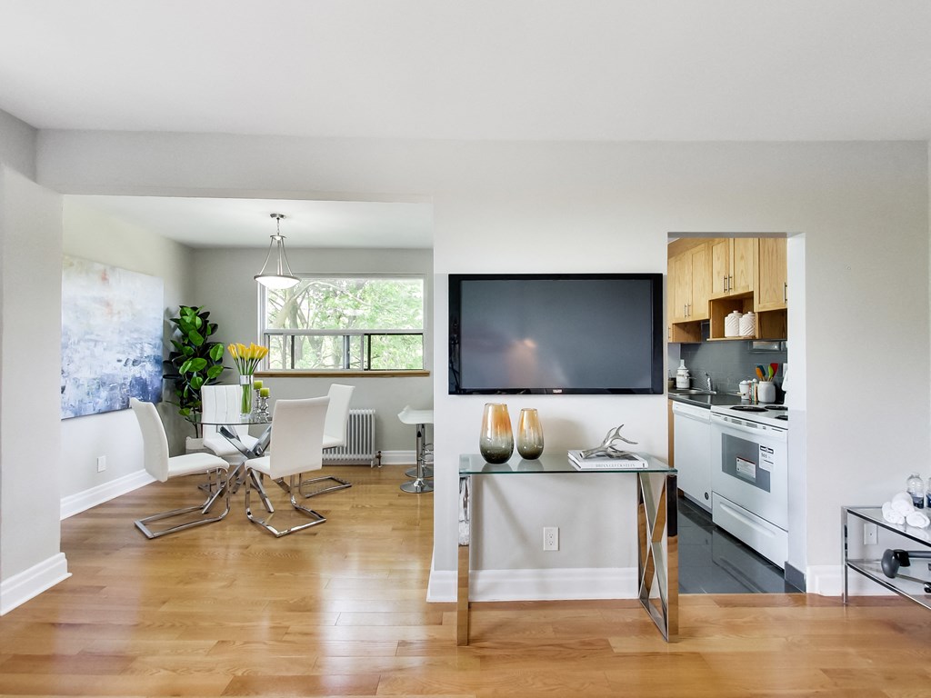 A modern kitchen with a glass table and white chairs.