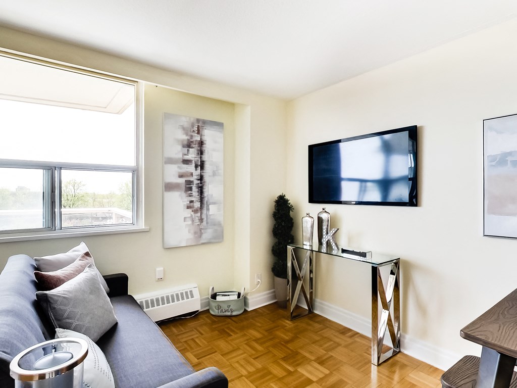 A living room with a blue couch and a television on the wall.