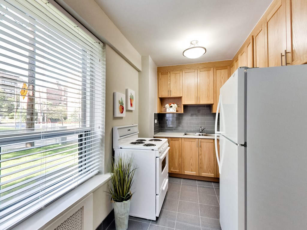 a kitchen with white appliances and wood cabinets and a large window