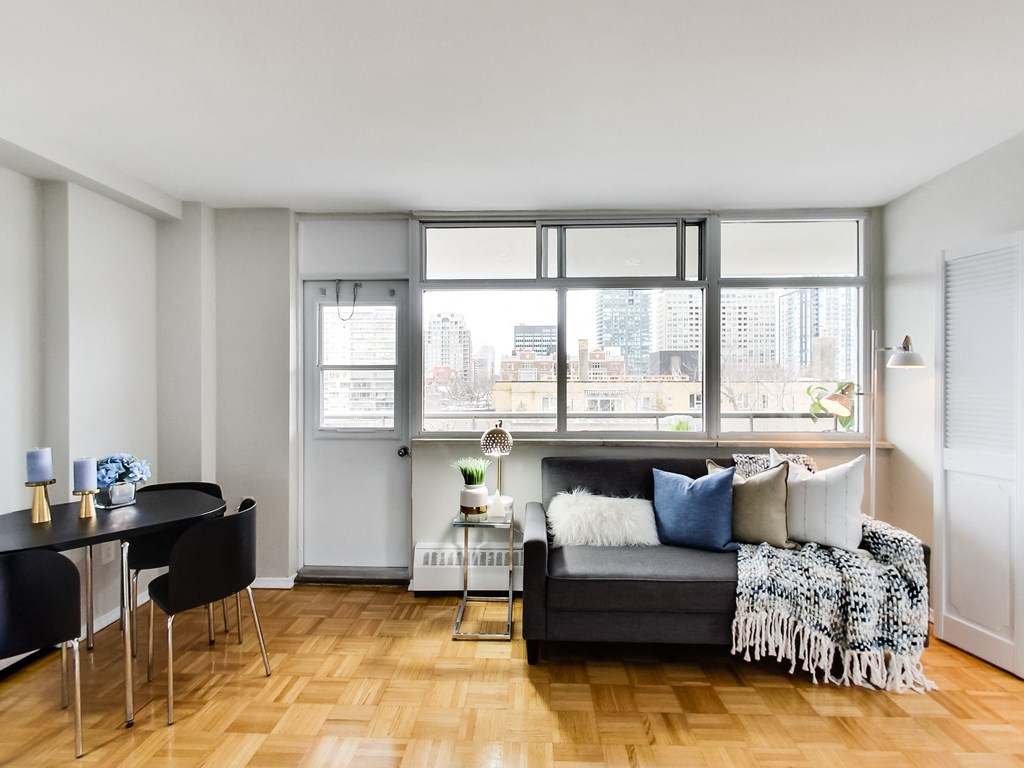 A living room with a black couch and a table with chairs.