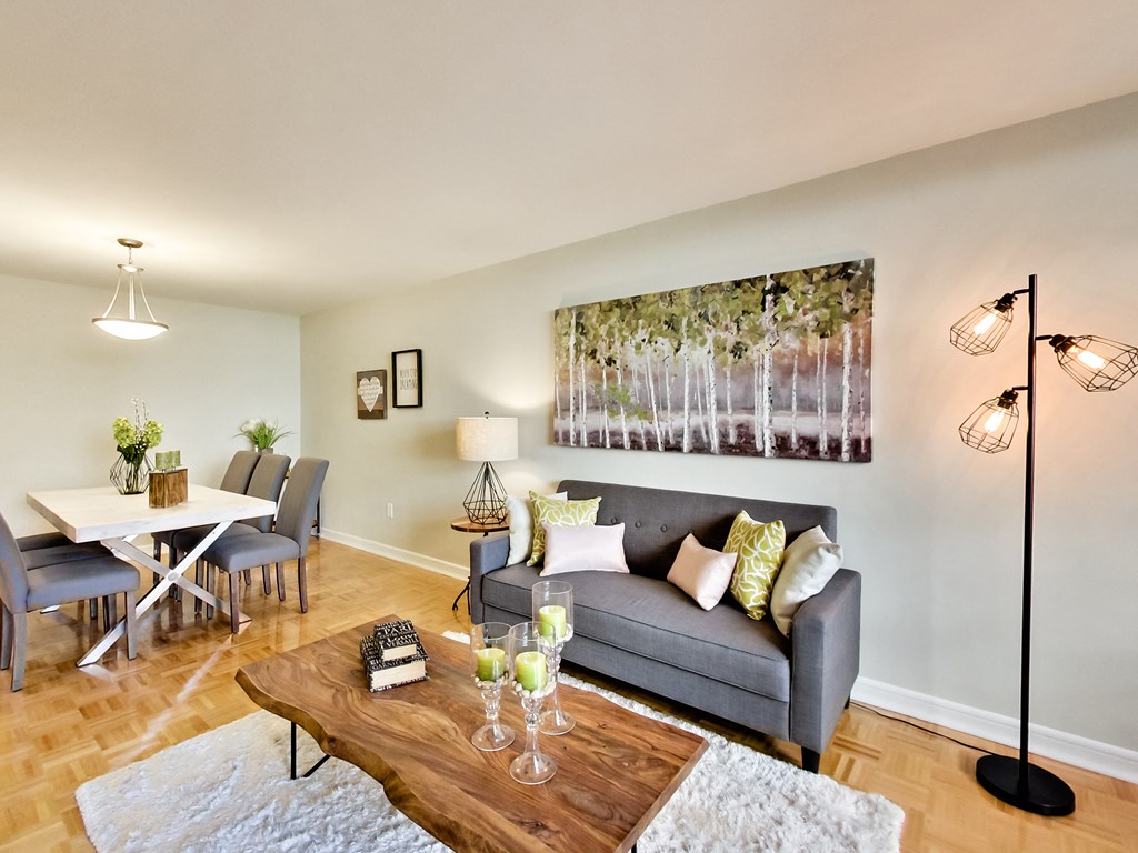 A living room with a grey couch, a wooden coffee table, and a large painting on the wall.