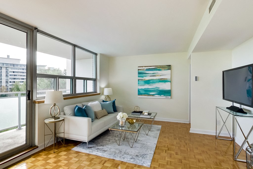 A living room with a white couch and a painting on the wall.