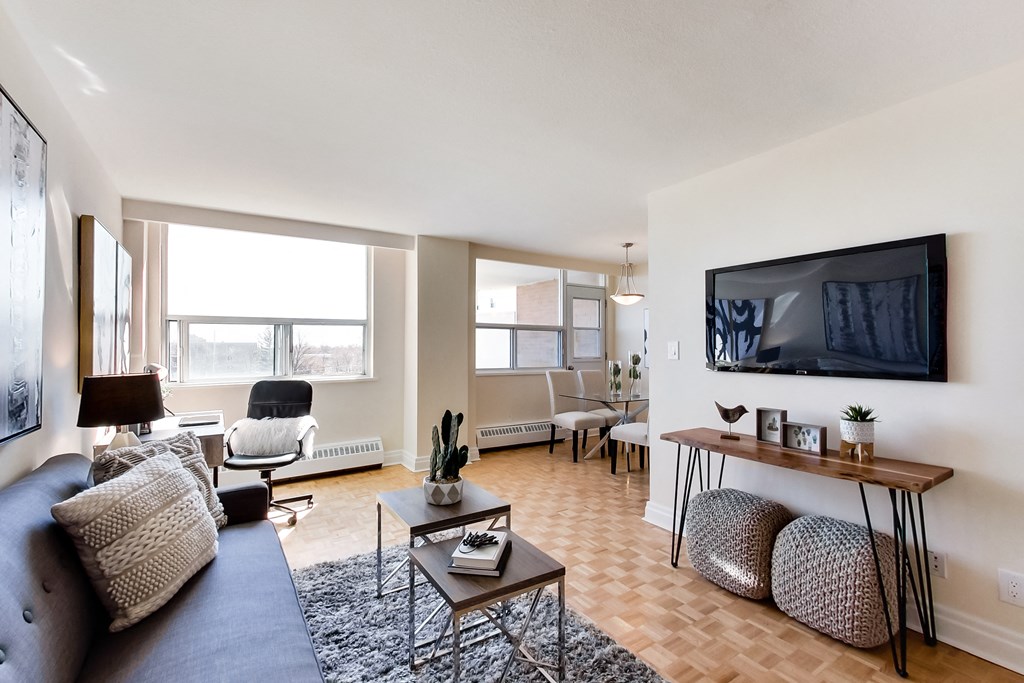 A living room with a grey couch, a black chair, a wooden table, and a television mounted on the wall.