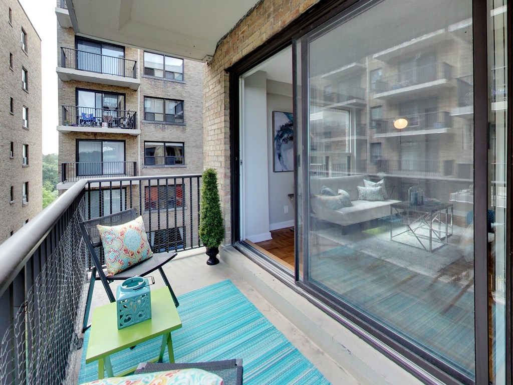 a balcony with a blue rug and chairs and a sliding glass door
