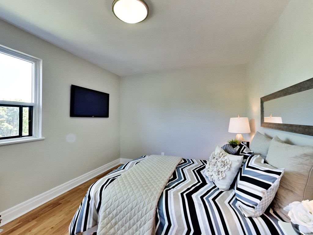 A bedroom with a bed, a television, and a window.