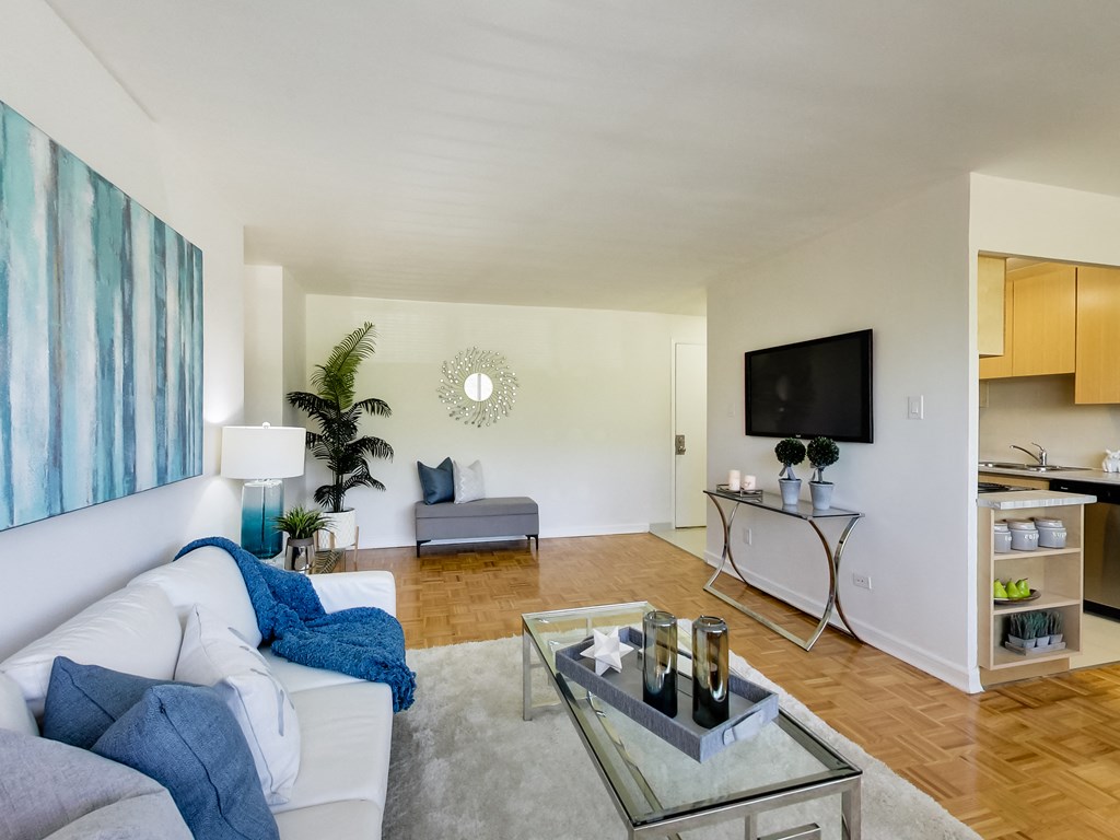 a living room with a white couch and a glass coffee table and a television