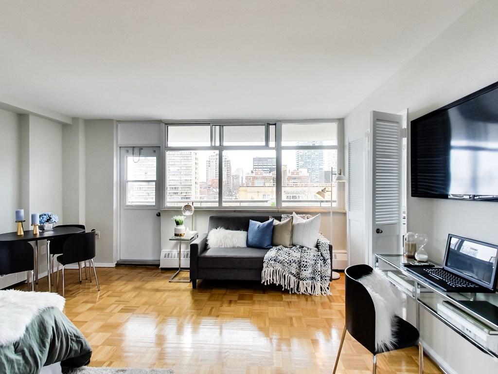 A modern living room with a black couch and a television on the wall.