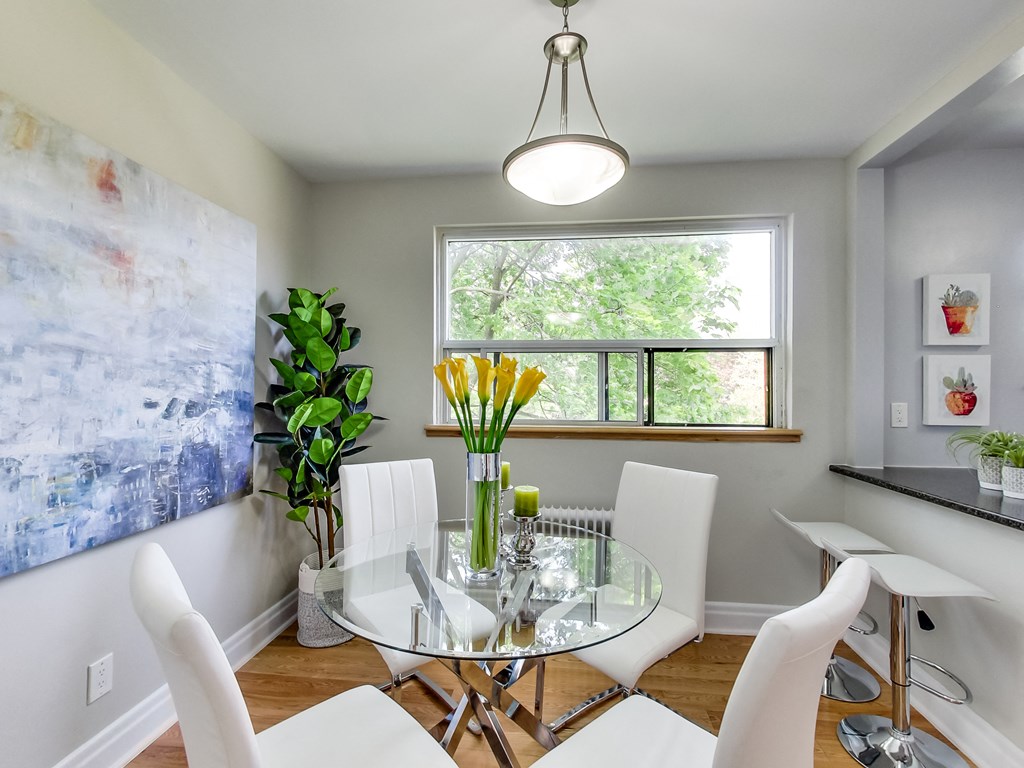 A dining room with a glass table and white chairs.