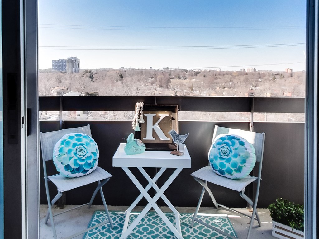 a balcony with three chairs and a table with two large pillows