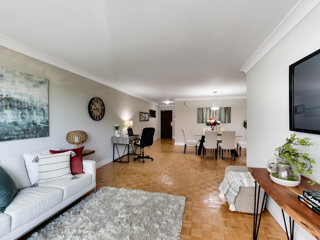 A living room with a white couch and a painting on the wall.