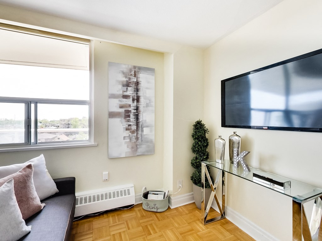 A living room with a couch, a television, and a painting on the wall.