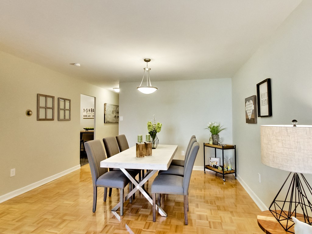 A dining room with a white table and grey chairs.