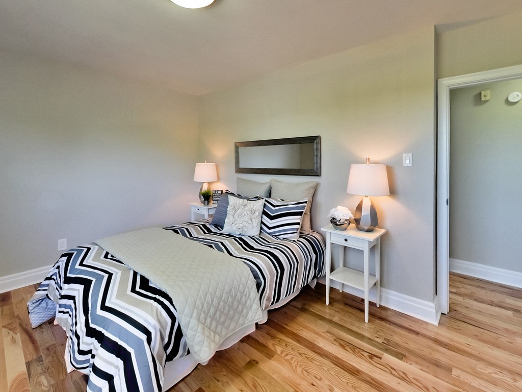 A bedroom with a bed, nightstands, and a mirror.