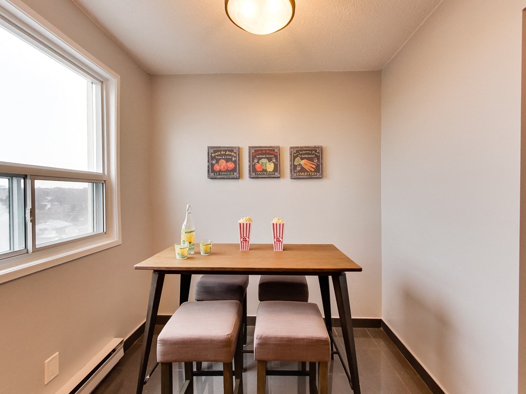 a dining room with a table and three chairs and a window