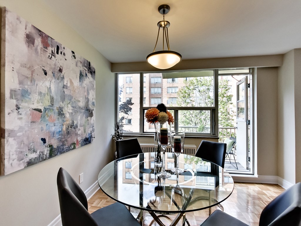 a dining room with a glass table and chairs and a large window