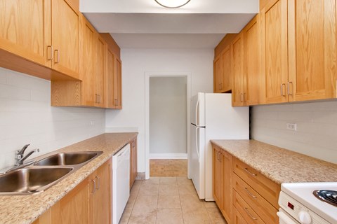 an empty kitchen with wooden cabinets and a white refrigerator