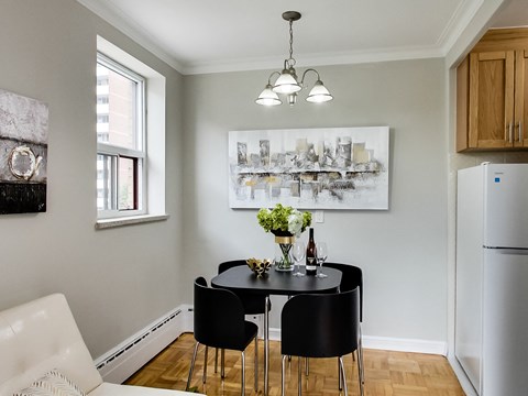 a dining room with a black table and chairs and a refrigerator