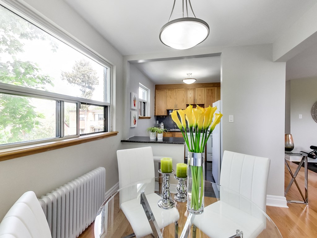 A dining room with a table set for two and a vase of yellow flowers.