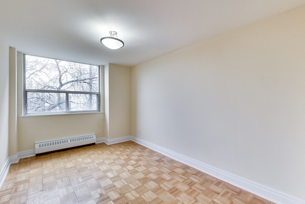 A room with a window and a radiator on the floor.