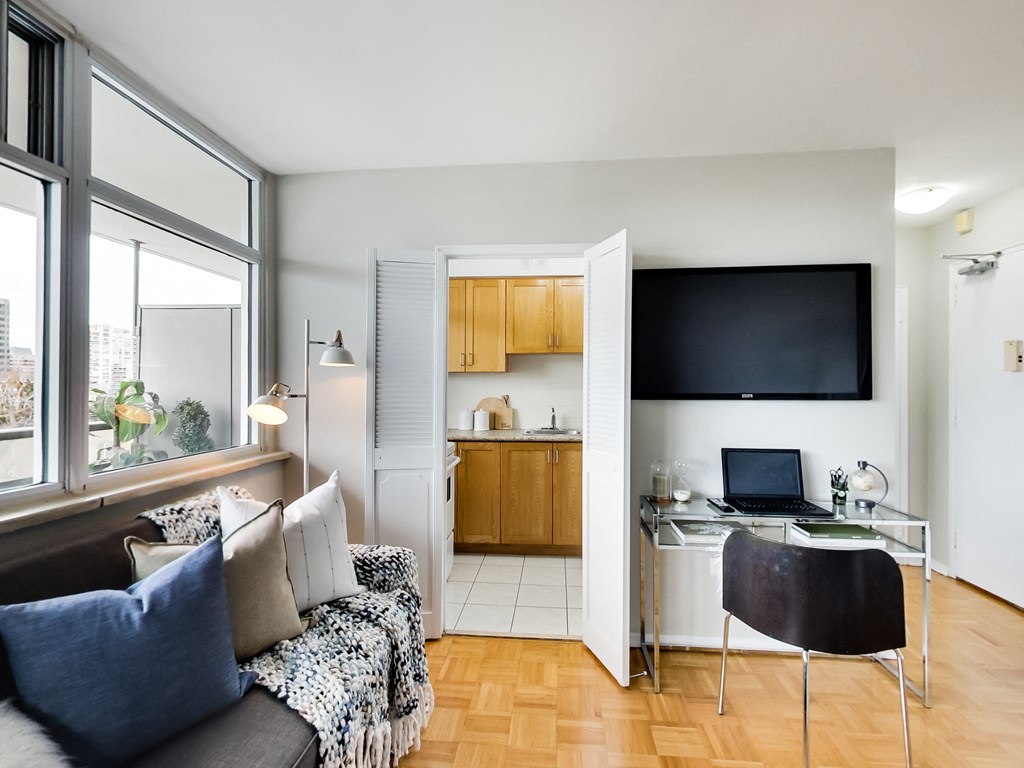 A room with a couch, a chair, a desk, and a television.