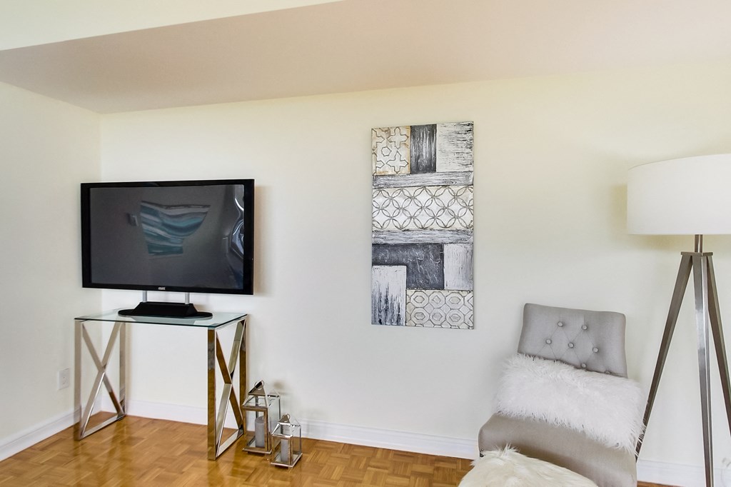 A modern living room with a television, a chair, and two pieces of artwork on the wall.
