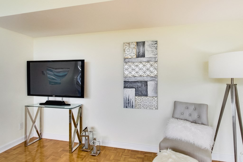 A modern living room with a television, a chair, and two pieces of artwork on the wall.