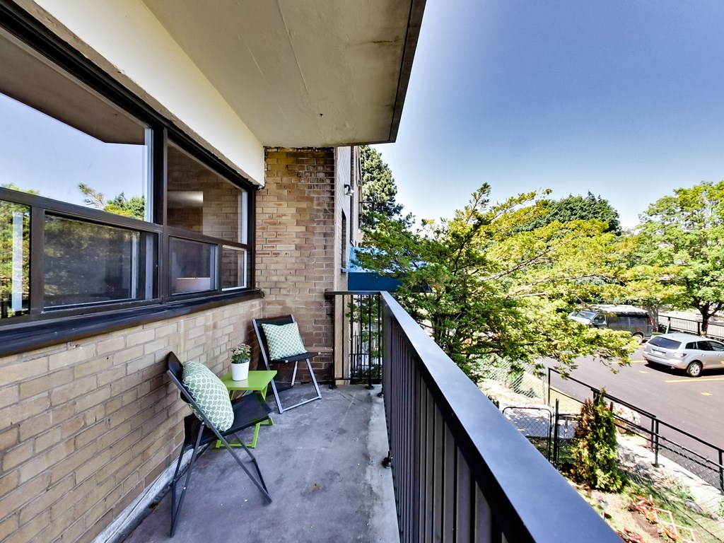 A balcony with a table and chairs overlooking a street.