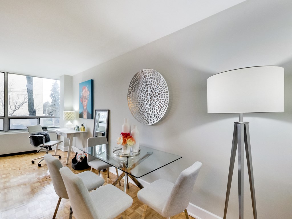A modern dining room with a glass table and white chairs.
