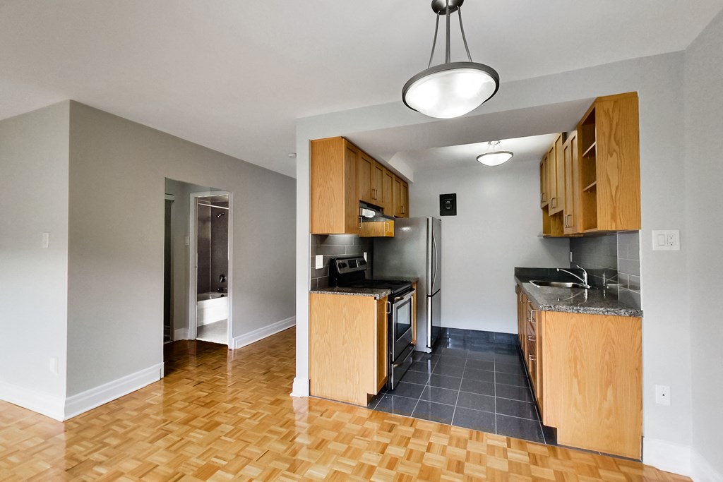 a view of an empty kitchen with wood cabinets and a stainless steel refrigerator