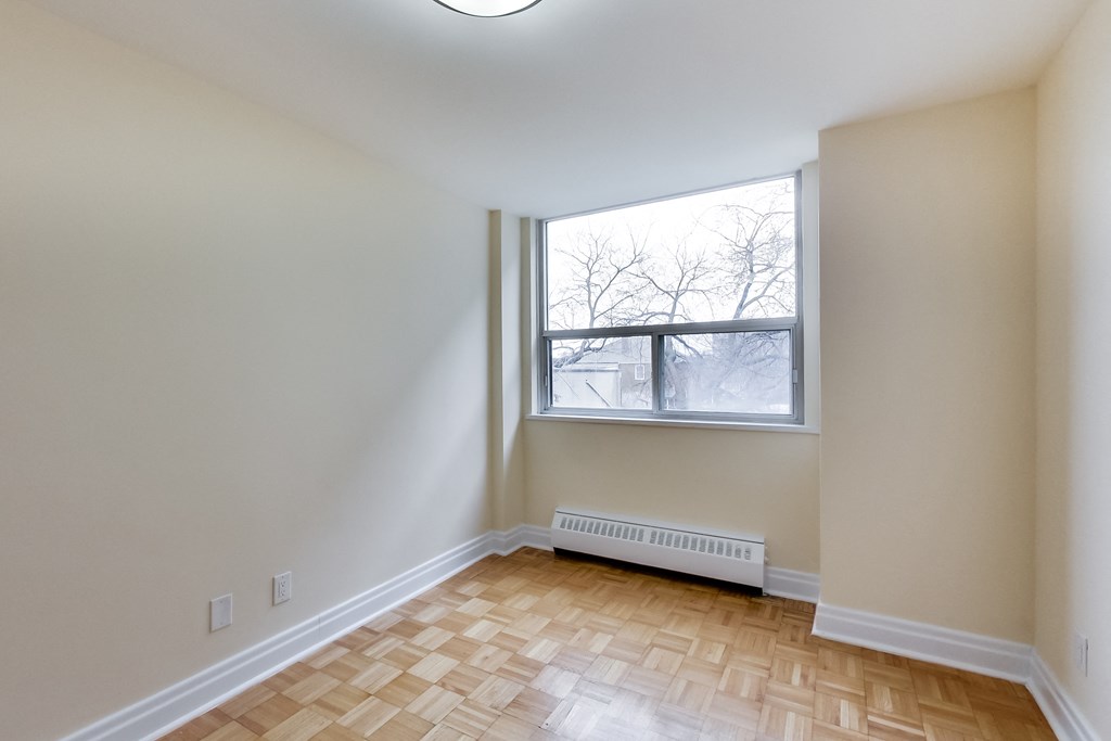 A room with a window and a radiator on the floor.