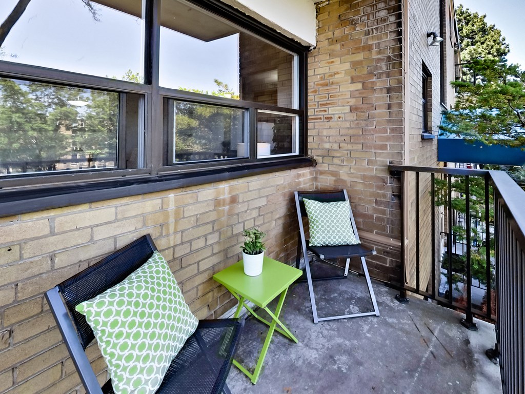 A balcony with a green table and two chairs.
