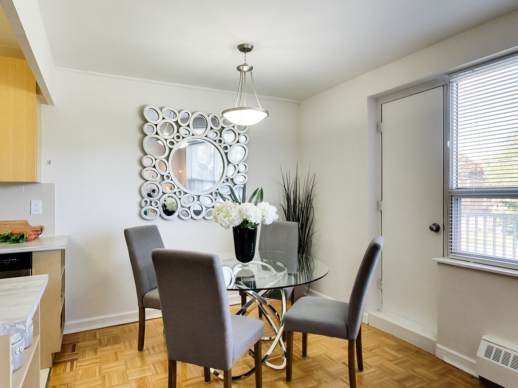 a dining room with a glass table and chairs and a mirror