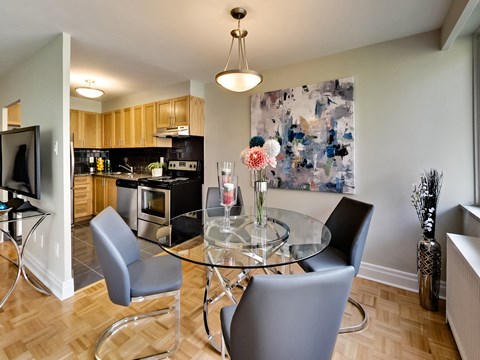 A modern kitchen with a glass table and grey chairs.