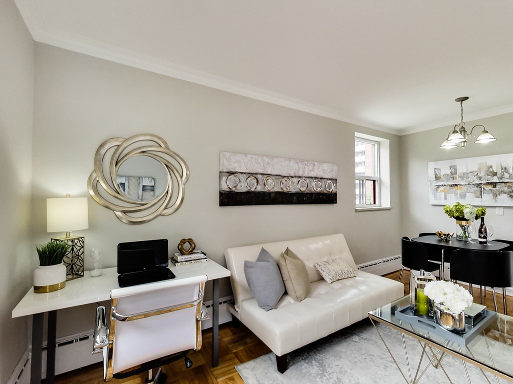 a living room with a white couch and a desk with a laptop