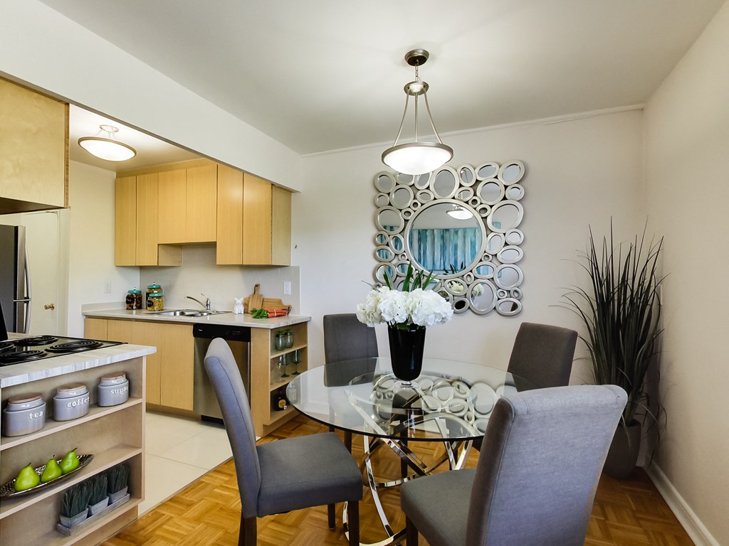 a dining room with a glass table and chairs and a kitchen with a sink and