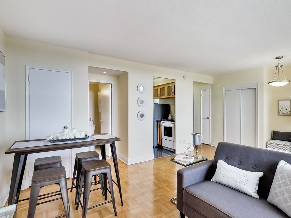 A modern living room with a grey couch and a wooden dining table.