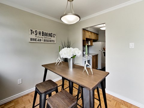 A dining area with a table and chairs and a sign on the wall.