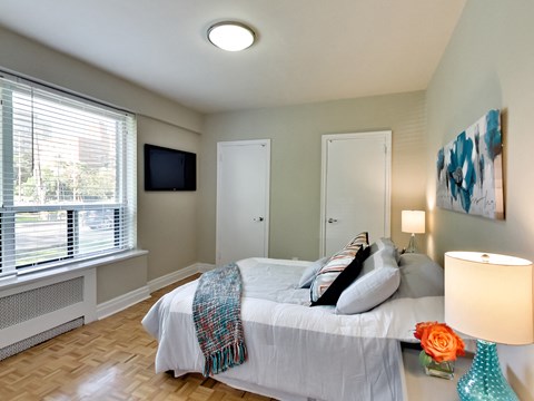 a bedroom with a bed and a tv on the wall