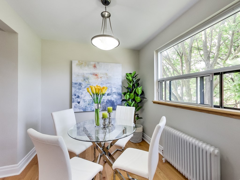 A dining room with a glass table and white chairs.