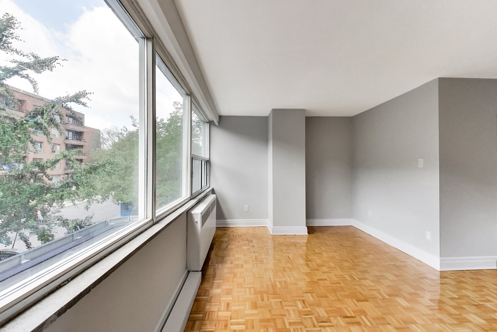 an empty living room with a large window and wood flooring