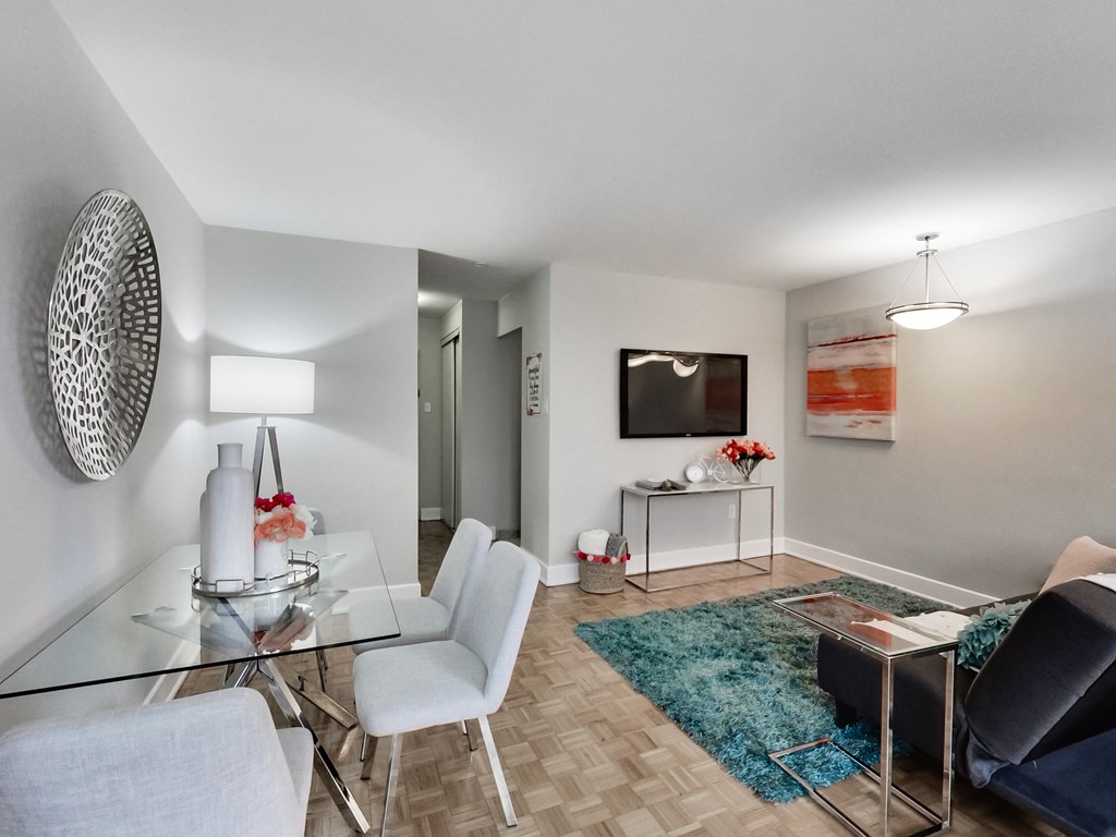 A modern living room with a glass table and white chairs.