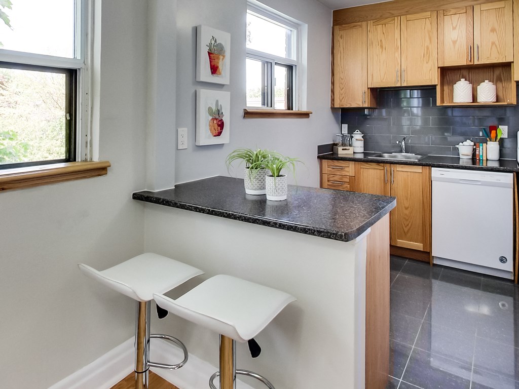 A kitchen with a black countertop and white stools.