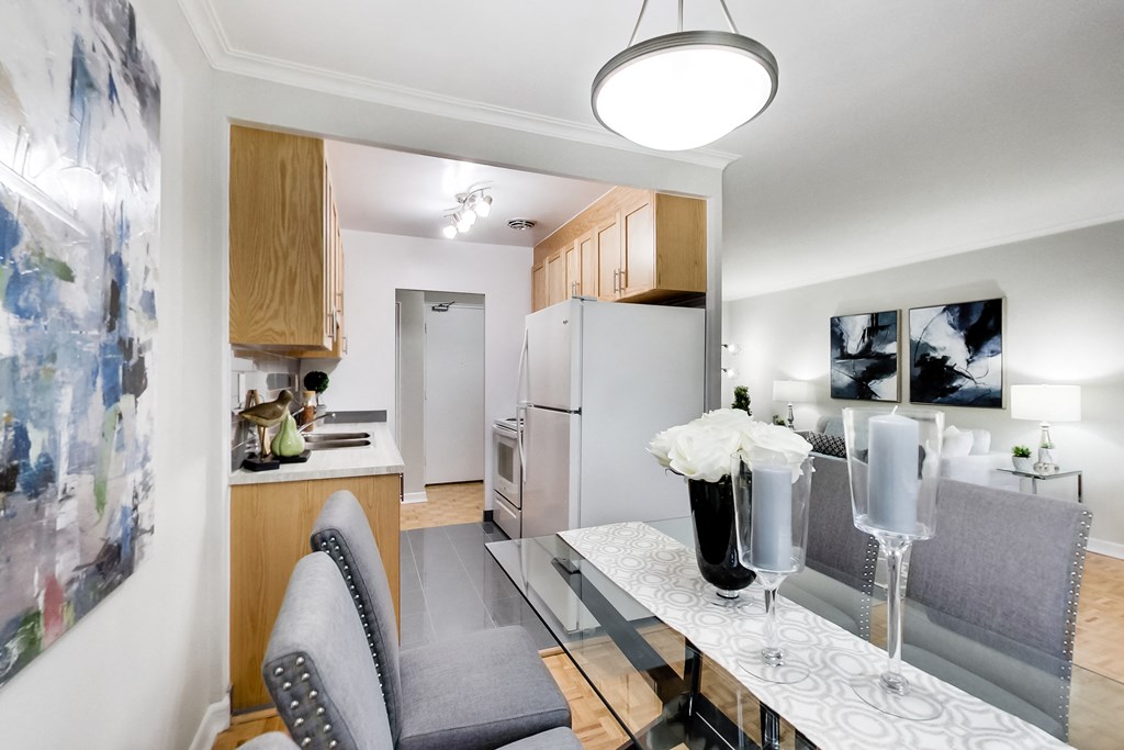 a living room with a dining room table and a kitchen with a refrigerator