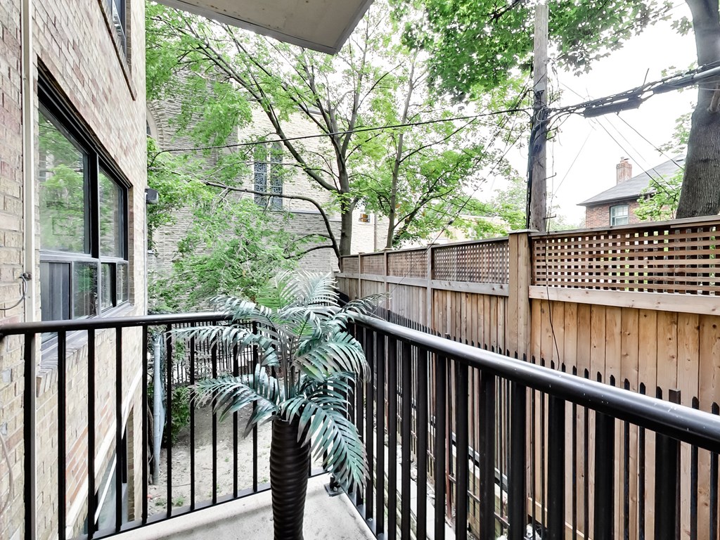 the balcony has a view of the yard and the trees