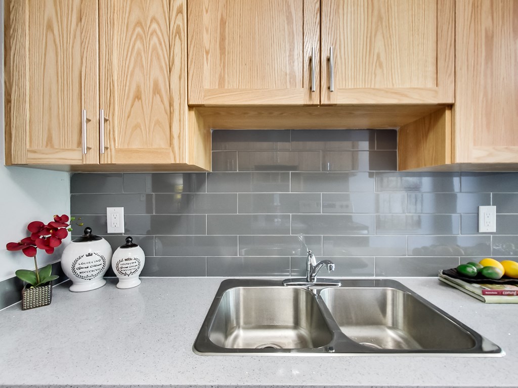 A kitchen with a sink and wooden cabinets.