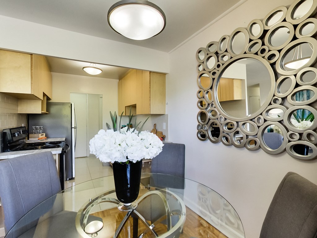 a dining room with a glass table with a vase of flowers